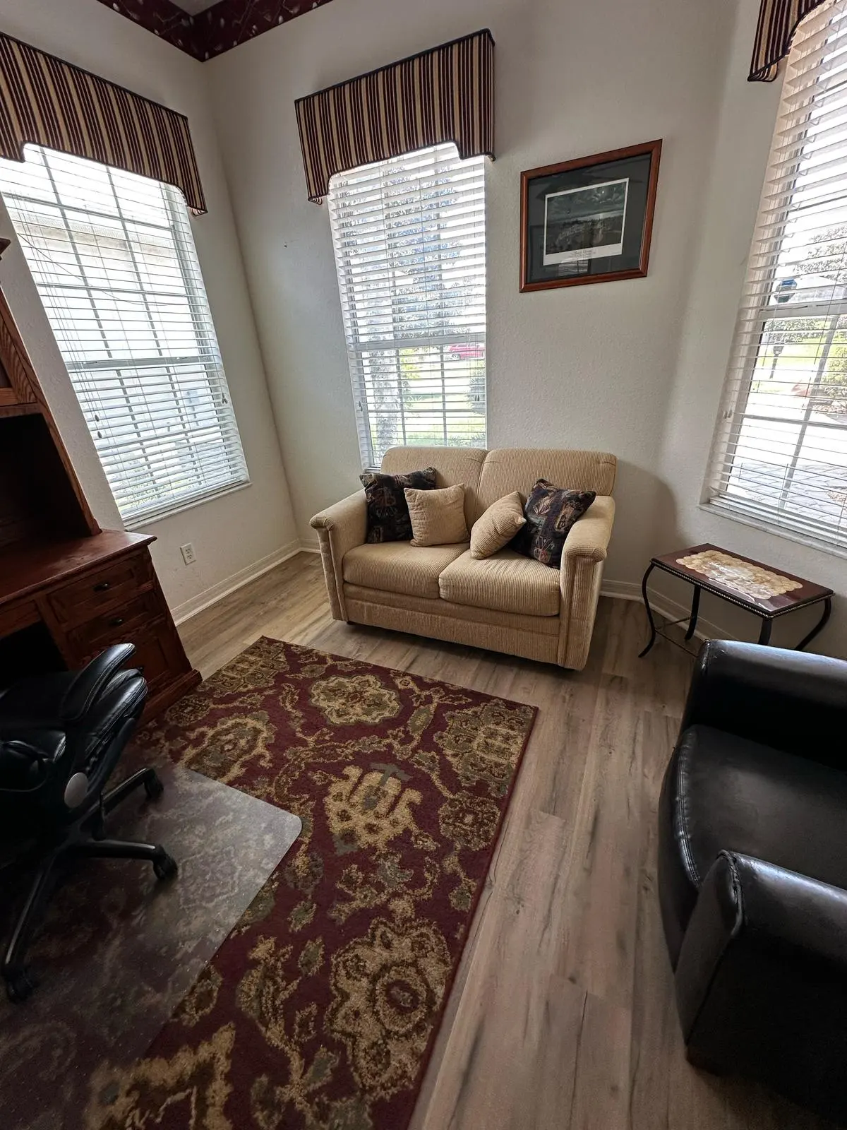 Living room with wood-look flooring and tall windows in a Summerfield, FL home