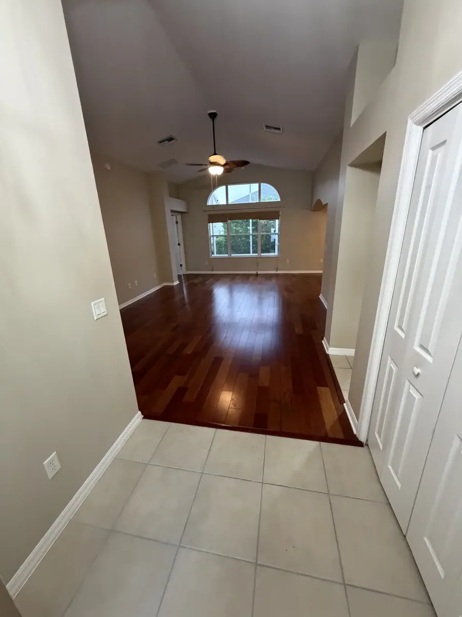 Hallway meeting tile and cherry-toned wood flooring in a Summerfield, FL home
