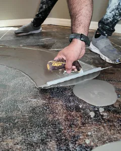 Installer smoothing a leveling compound on a concrete slab